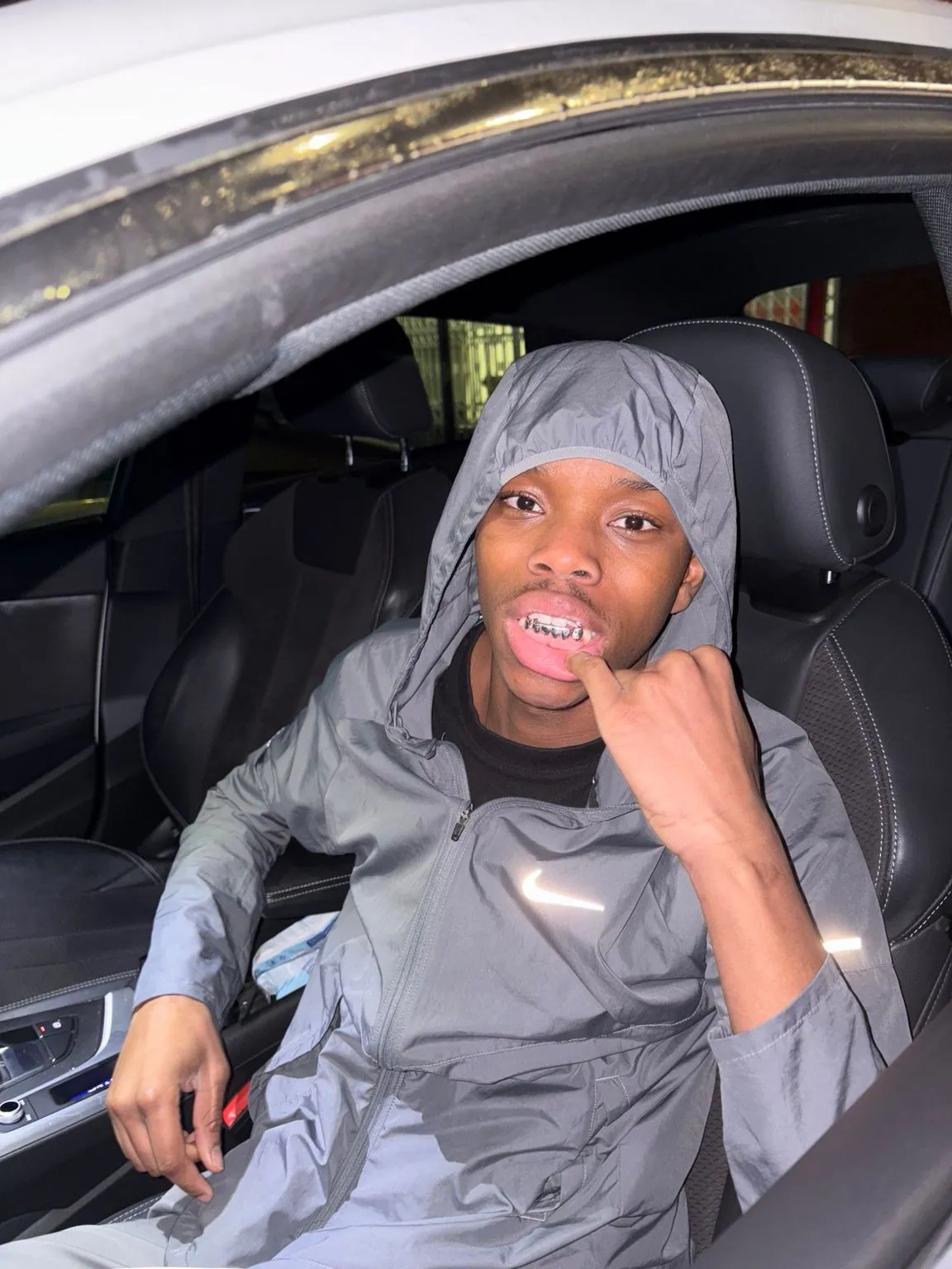A Matrix client in a car pointing to his grillz
