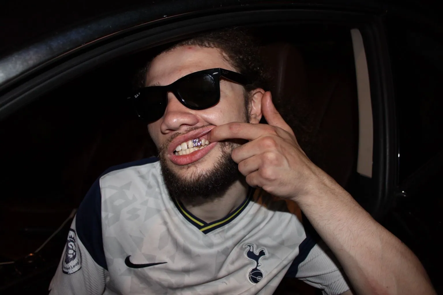 A Matrix client in sunglasses pulling his lip to show a custom grillz set