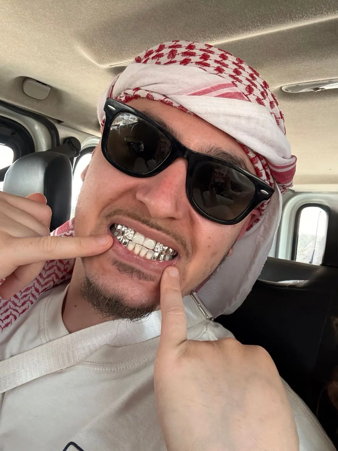 A Matrix client in sunglasses and a headscarf pointing to a silver grillz set